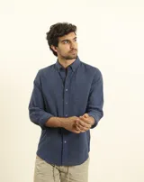 Camisa azul marino de lino y algodón, con cuello abotonado, manga larga con puños enrollados, bolsillo de parche en el pecho y cierre frontal con botones.