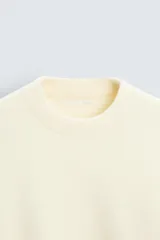 Jersey color crema de punto con textura, cuello redondo, manga larga y corte relaxed fit.