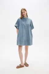 Vestido corto de jean celeste, de corte holgado, manga corta y cuello redondo.