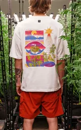 Remera blanca de corte extra oversize con hombros caídos, cuello redondo de rib al tono y estampado con dibujos de plantas de marihuana en estilo cómic.