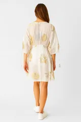 Túnica de algodón color crudo con estampado de motivos marinos en dorado. Tiene escote en V con cordones y mangas 3/4 con lazos.