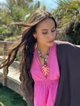 Collar corto con cuentas de cerámica y acrílico de colores, tiento sintético y dije de resina en forma de hoja de palmera color coral.