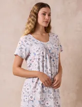 Camisón corto negro con lunares blancos, de tejido suave y escote redondo con detalle plisado y moño blanco.