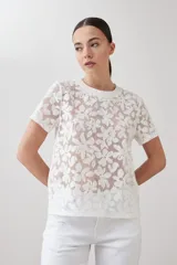 Blusa blanca de encaje con mangas cortas y cuello redondo.