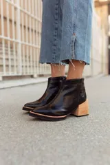 Botines negros de cuero sintético con puntera fina, cierre lateral y tacón de madera.