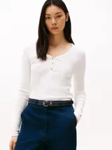 Remera blanca de algodón con textura acanalada, corte slim, cuello redondo con tapeta de botones dorados y manga larga.