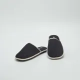 Pantuflas mules negras con borde gris.