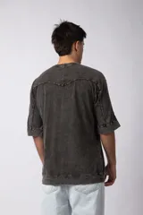 Remera oversize de algodón pesado, color gris oscuro con efecto lavado 'snow' que le da un aspecto gastado y único. Presenta cuello redondo y costuras vistas en hombros y mangas.