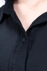 Camisa negra de manga corta con cuello clásico, bolsillo en el pecho y corte holgado.