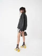 Chaqueta bomber larga oversize de color negro, con sisa amplia y mangas globo, botones de presión y dos bolsillos laterales.