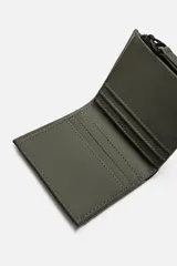 Billetera color verde militar con acabado engomado, monedero con cierre de cremallera, compartimento principal para billetes, seis posiciones internas para tarjetas y dos externas.