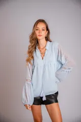 Camisa blanca de plumetí con cuello mao, mangas largas abullonadas con puños elásticos y cordón con borlas en el escote.