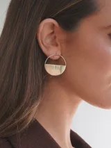 Par de aros dorados con forma circular, divididos horizontalmente: la mitad superior es un aro fino y la mitad inferior es un semicírculo sólido.