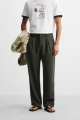 Pantalón verde oscuro de corte amplio confeccionado en tejido de lyocell. Presenta pliegues frontales, bolsillos laterales y traseros de ojal. Cierre frontal con cremallera y botón.