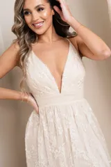 Vestido largo de fiesta color champagne, con escote en V profundo, breteles finos y falda con abertura lateral. El vestido está confeccionado en tul bordado con flores y lentejuelas.