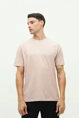 Remera verde de manga corta con cuello redondo y estampado en la espalda con la frase "Côte d'Azur Surfer avec les mouettes" y un dibujo de una sombrilla, una reposera y gaviotas.