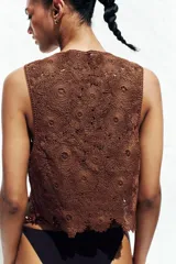 Top chaleco marrón de crochet con escote en pico y cierre frontal con lazos.