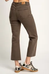Pantalón jean marrón de corte flare, tiro medio y terminación desflecada.
