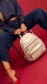 Mochila color rosa de símil cuero con bolsillos frontales con cierre. Tiene asa de mano rígida y correas regulables.