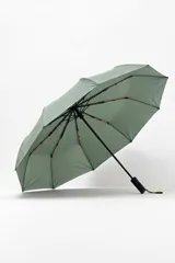 Paraguas plegable de color verde salvia, con estructura y varillas negras. El mango es negro y tiene una correa de tela para colgar.