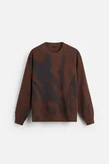 Sweater marrón de punto con cuello redondo y manga larga. Tiene un estampado irregular con efecto spray en color azul.