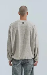 Sweater de punto color gris claro, de corte holgado, con cuello redondo y puños con elástico.