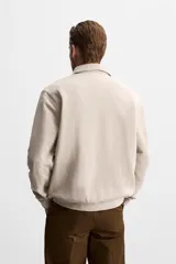 Polo manga larga gris con cuello solapa y cierre frontal de botonadura.