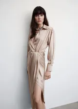 Vestido midi satinado color beige, con manga larga, cuello cruzado y abertura lateral.