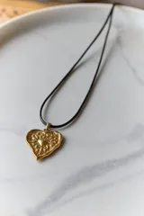 Collar con tiento encerado negro y dije dorado con forma de corazón texturizado.