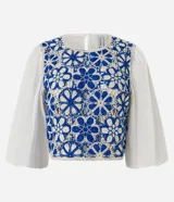 Blusa con cuerpo de tejido de ganchillo (crochet) bicolor azul y blanco con diseño floral, mangas largas abullonadas de tejido liso blanco y cuello redondo.