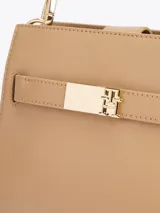 Cartera satchel color beige con asa superior extraíble y correa ajustable y extraíble. Tiene cierre magnético, dos compartimentos principales y un compartimento interior con cremallera.