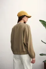 Chaqueta bomber negra con cierre frontal dorado y mangas largas con puños elásticos.