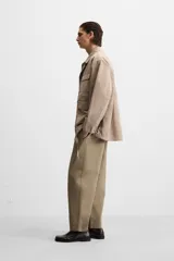 Pantalón de hombre color beige, corte carrot fit, con cintura elástica ajustable con cordón, bolsillos frontales y bolsillo trasero de plastrón.