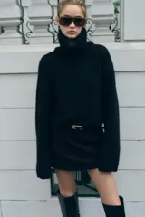 Sweater azul de tejido de punto grueso, con cuello alto y mangas largas acampanadas.