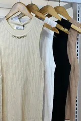 Musculosa blanca de hilo con cuello redondo y detalle de cadena dorada.