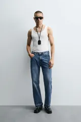 Pantalón de jean celeste de corte flare, con tiro medio, cinco bolsillos, cierre frontal con cremallera y botón, y bajo con acabado irregular.