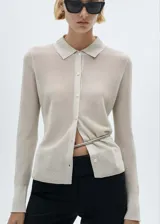 Cárdigan de punto fino color beige con lurex, cuello camisero, cierre frontal con botones y corte entallado.