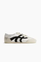 Zapatillas deportivas H&M color blanco con detalles en negro y beige. Confeccionadas en cuero sintético y gamuza, con cordones y suela de goma.
