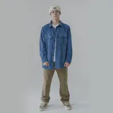 Camisa celeste de pana con corte oversize, cuello clásico, cierre frontal con botones, dos bolsillos con solapa en el pecho y mangas largas con puños abotonados.