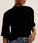 Blusa boxy de terciopelo negro con cuello alto y mangas cortas amplias.