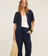 Pantalón largo color verde oliva, de corte pijama, confeccionado en malla orly. Presenta cintura elástica con lazo, bolsillos laterales tipo cargo y corte fluido.