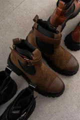 Botas de cuero color marrón oscuro, estilo Chelsea, con elástico lateral negro y suela track negra. Incluye correa de cuero desmontable con hebilla.