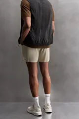 Shorts deportivos marrones de tejido técnico ligero y elástico con diferentes estructuras. Tiene forro interior, cintura elástica ajustable con cordón, bolsillos frontales, bolsillo trasero con cierre, aberturas laterales y logo estampado en la pierna.