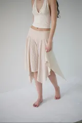 Falda elastizada de encaje color crema, con cintura alta y bajo irregular.