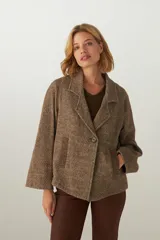 Saco corto de tela patchwork en tonos marrones, con manga ranglan, cuello con solapas y ruedo irregular.