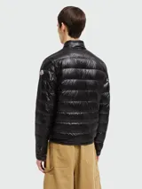 Campera puffer Moncler modelo Acorus, color verde oscuro, de corte entallado y largo a la cadera. Confeccionada en tejido técnico acolchado, cierre frontal con cremallera, cuello mao y bolsillos laterales con cremallera. Plegable y fácil de transportar.