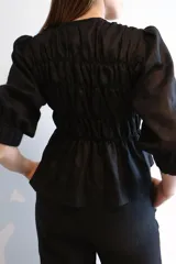 Blusa fruncida de 100% lino, con botones de nácar y puños elásticos.