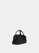 Bolso bowling de piel granulada color negro, marca Jacquemus, modelo Le Petit. Tiene cierre con cremallera bidireccional y bolsillo interior. Incluye bandolera ajustable y extraíble, y detalle de lazo decorativo en el frente.