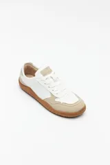 Zapatillas de cuero color blanco y beige, de diseño minimalista con suela marrón.
