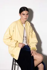 Campera bomber color amarillo pastel de cuero vacuno, con cierre delantero y bolsillos. Tiene puños, cuello y pretina de algodón.
